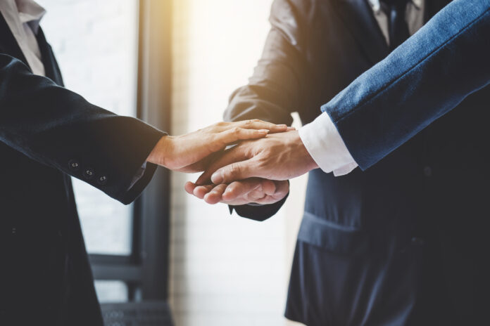 Image of business people joining and putting hands together duri