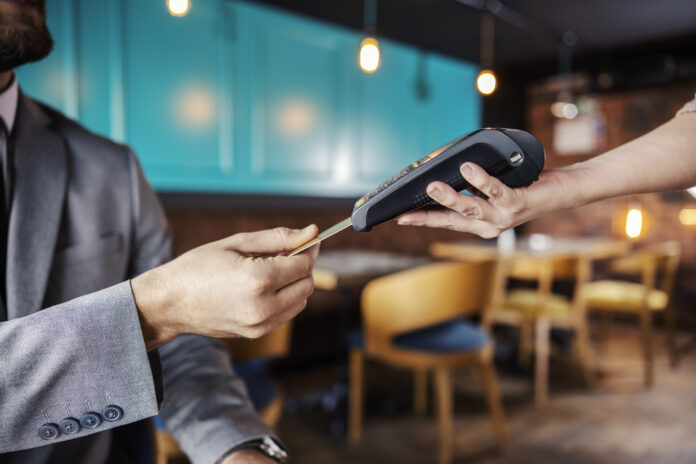 Hands holding a payment terminal. A man elegantly dressed in a b
