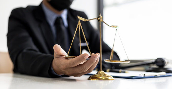 The male lawyer puts a second hand on the scales of justice on h