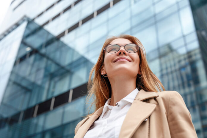 Happy young bussines woman standing outside modern office building