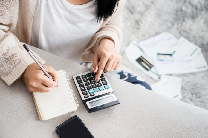 woman writing a list of debt on notebook calculating her expense